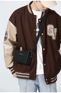 Detail view of black crocodile pattern mini crossbody bag worn by a male model