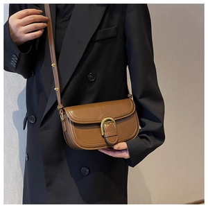 Model wearing a vintage brown saddle bag with a large gold buckle over a black blazer