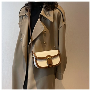Detail of vintage saddle bag with cream body, brown leather trim and golden buckle