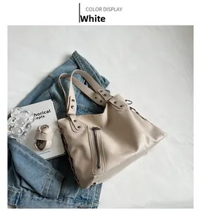 Detailed close-up of a white PU leather tote bag with vertical zipper and metal rivets