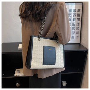 Détail d'un sac cabas en toile avec bandoulière chaîne et poche imprimée sur fond sobre