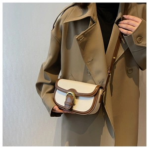 Close-up of vintage saddle bag in beige leather with brown trim and adjustable shoulder strap