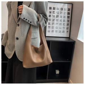 Gros plan du cabas en cuir marron caramel porté avec un blazer gris à rayures