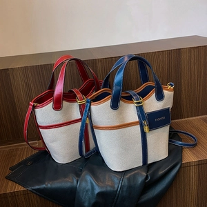Close-up of canvas bucket bag featuring contrast leather trim and golden metal lock detail