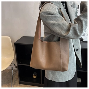 Détail d'un sac Hobo marron en cuir grainé avec large bandoulière porté sur un blazer