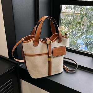 Detailed view of canvas bucket bag featuring leather trim, fashion tag and gold lock