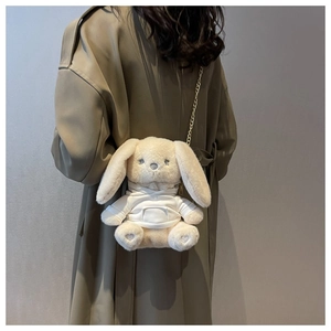 Détail du sac peluche lapin mignon avec chaîne dorée sur une tenue de manteau kaki