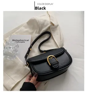 Detail of vintage black saddle bag with gold horseshoe buckle on a white blazer background