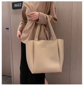 Close-up of a large beige PU leather tote bag worn on shoulder for daily commute