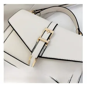 Close-up of white envelope bag with golden metal buckle and black edge finishing