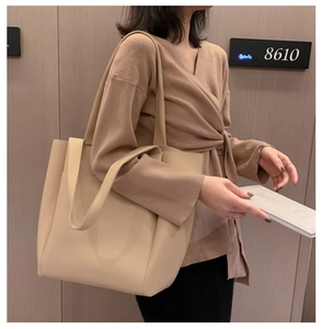 Close-up of beige PU leather tote bag with double straps worn on shoulder for commuting
