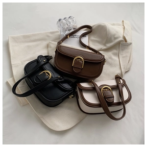 Detailed view of vintage saddle bags in three colors with gold horseshoe buckles