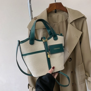 Close-up of canvas bucket bag with green leather trim and golden padlock detail