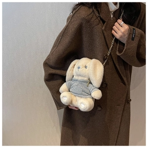 Détail d'un sac bandoulière lapin en peluche avec chaîne sur une tenue de manteau