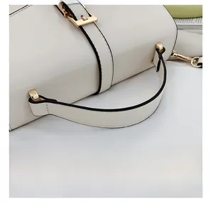 Close-up of the beige handbag featuring a comfortable handle and gold metal hardware