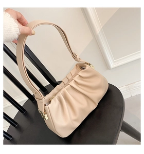 Detailed view of beige pleated shoulder bag with soft cloud texture and gold metal hardware