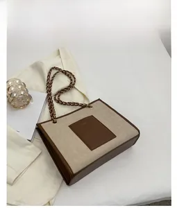 Détail du sac cabas beige matelassé avec poche en cuir marron et chaîne dorée