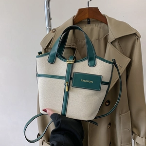 Detail of canvas bucket bag with green leather trim and elegant gold padlock decor
