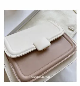 Detail of minimalist two-tone crossbody bag with square buckle and fine stitching