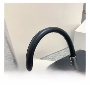 Close-up of black leather handbag featuring round handle and silver metallic square lock