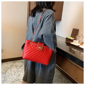 Dettaglio borsa trapuntata rossa con catena oro indossata su cappotto di lana grigio scuro