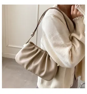 Detail of a beige pleated cloud bag with elegant gold metal hardware and slim strap