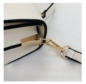 Detail of premium gold-toned metal hardware and beige leather on a crossbody bag
