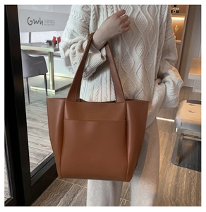 Brown soft PU leather tote bag with functional front pocket shown in a lifestyle setting