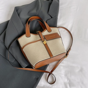 Close-up of canvas bucket bag with brown leather trim and golden square lock