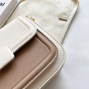 Detail of neat stitching on a beige and light coffee leather crossbody bag