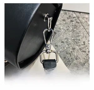 Detailed close-up of the silver metal hook and leather strap attachment of the black bag