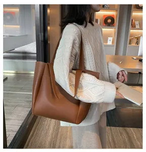 Close-up of caramel brown oversized PU leather tote bag with minimalist stitching details
