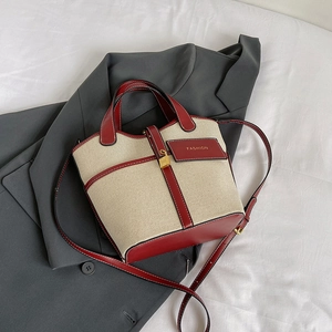 Detail of canvas tote bag showing fashion leather tag and golden clasp on grey suit