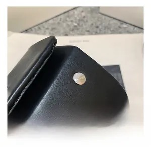 Close-up of black lychee grain leather handbag with round silver magnetic buckle