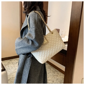 Dettaglio della borsa trapuntata beige con tracolla a catena d'oro e chiusura girevole