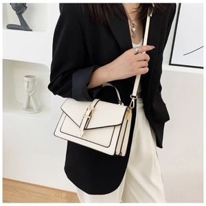 Close-up of cream crossbody bag with gold buckle and accordion fold side design