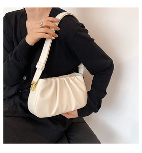 Detail view of cream pleated cloud bag with smooth faux leather texture and gold metal accents