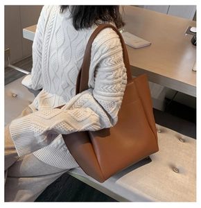 Detailed back view of a large brown PU leather tote bag worn over a white sweater