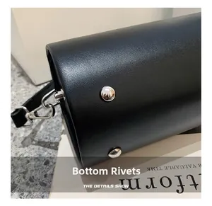 Close-up of black grainy leather bag base featuring protective silver bottom rivets