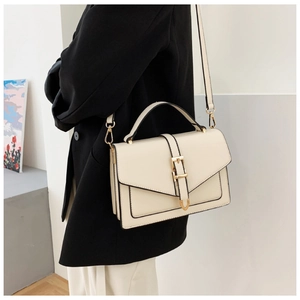 Detail of cream rectangular handbag with gold metal lock and black edge finish