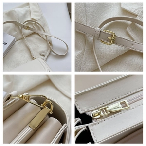 Detail view of cream leather crossbody bag with adjustable strap and gold metal buckles