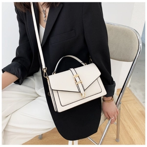 Detailed shot of a white crossbody bag with gold hardware and elegant black edging