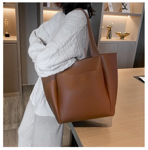 Close-up of caramel brown leather tote bag showing fine lychee texture and side pocket
