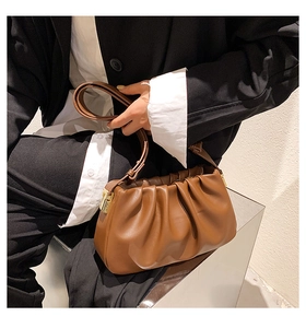 Detail of a brown pleated cloud bag with soft leather texture and golden metal buckle