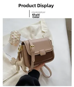 Detail of khaki leather crossbody bag with metal buckle and cute dog charm pendant