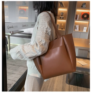Close-up of large brown matte PU leather tote bag with exterior pocket on a model