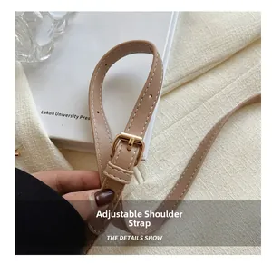 Detail of adjustable faux leather shoulder strap with white stitching and gold buckle
