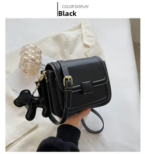 Close-up of black PU leather crossbody bag with white stitching and dog charm