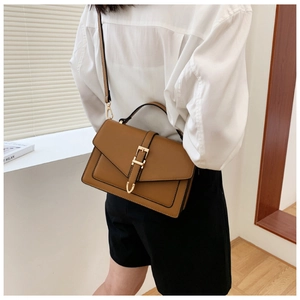 Caramel brown leather crossbody bag featuring an elegant gold buckle and top handle