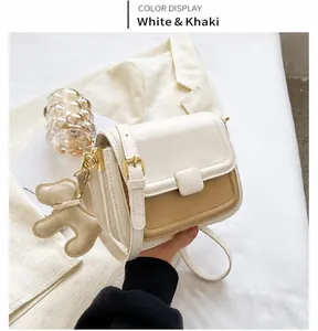 Detail of white and khaki crossbody bag with a cute dog pendant in a lifestyle setting